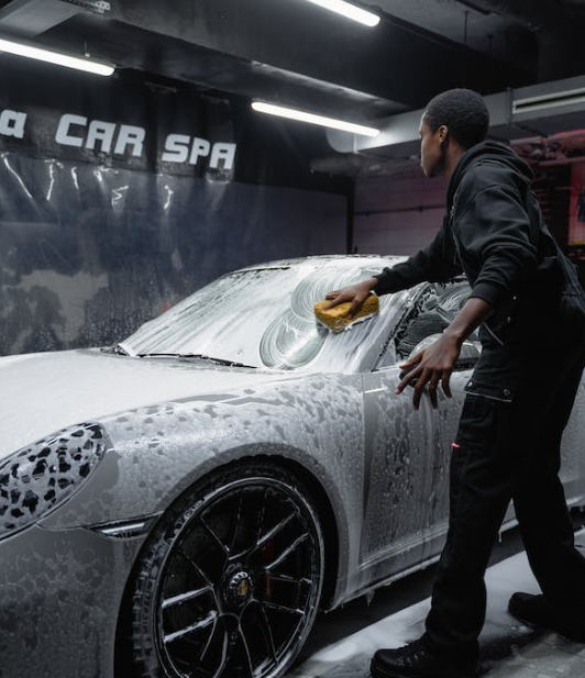 A screenshot image of a man working in a car wash. Cleaning a car