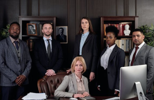 A screenshot of a female financial planner. Surrounded by her a staff. In a screenshot image